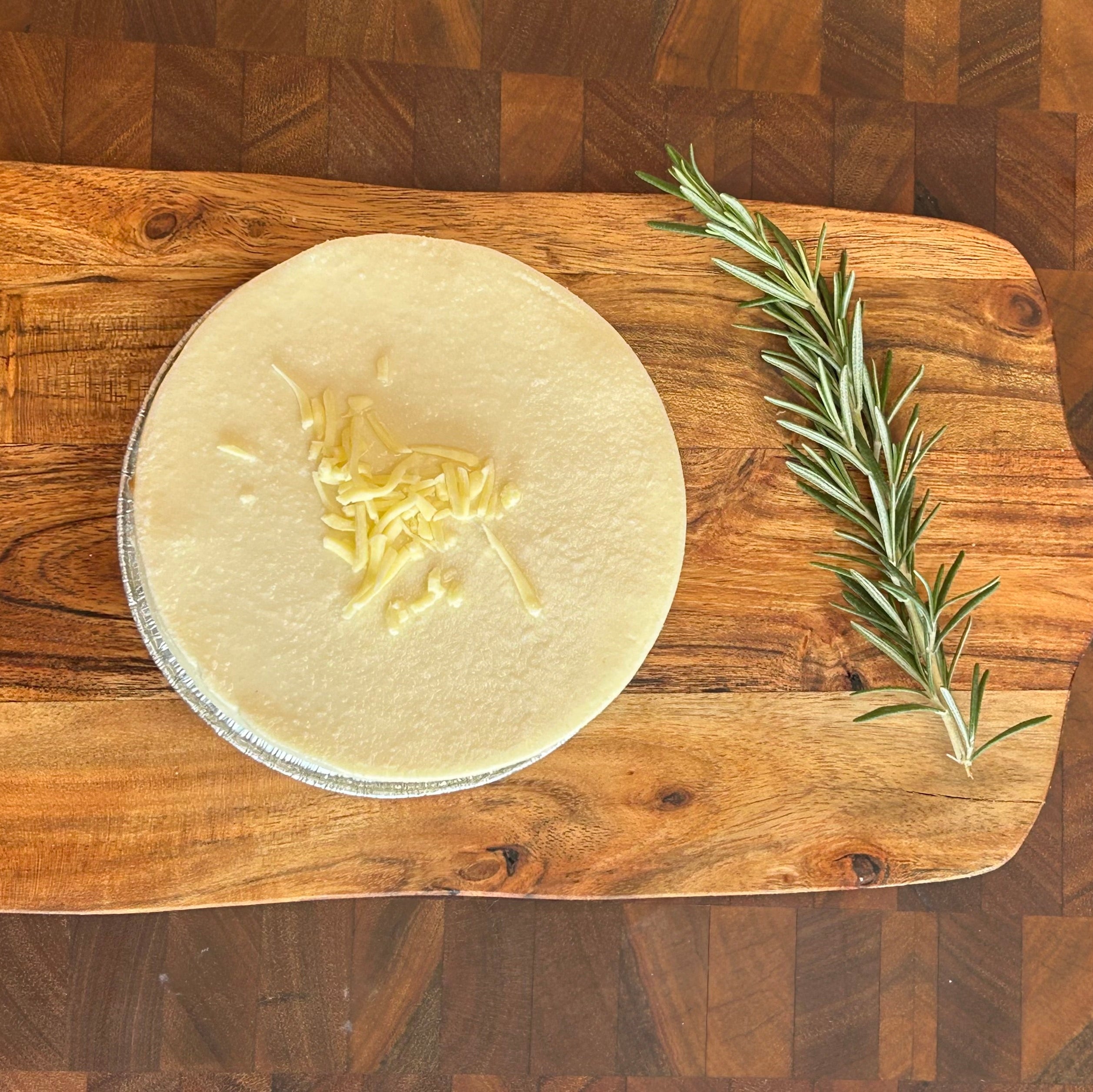 A cheeseburger brisket pie on a wooden cutting board, garnished with a sprig of dill, with cheese visible on top.